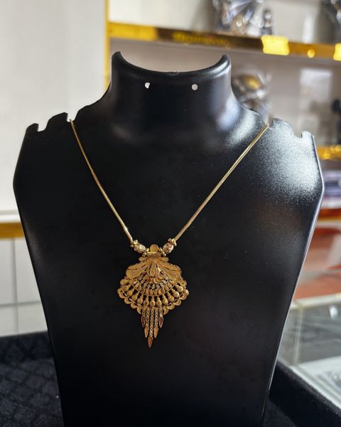 Gold kanthi with a fan-shaped pendant and drops, on a display bust
