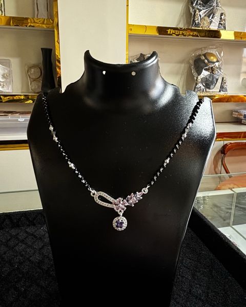 Mangalsutra with black beads and a curved pendant, on a display bust